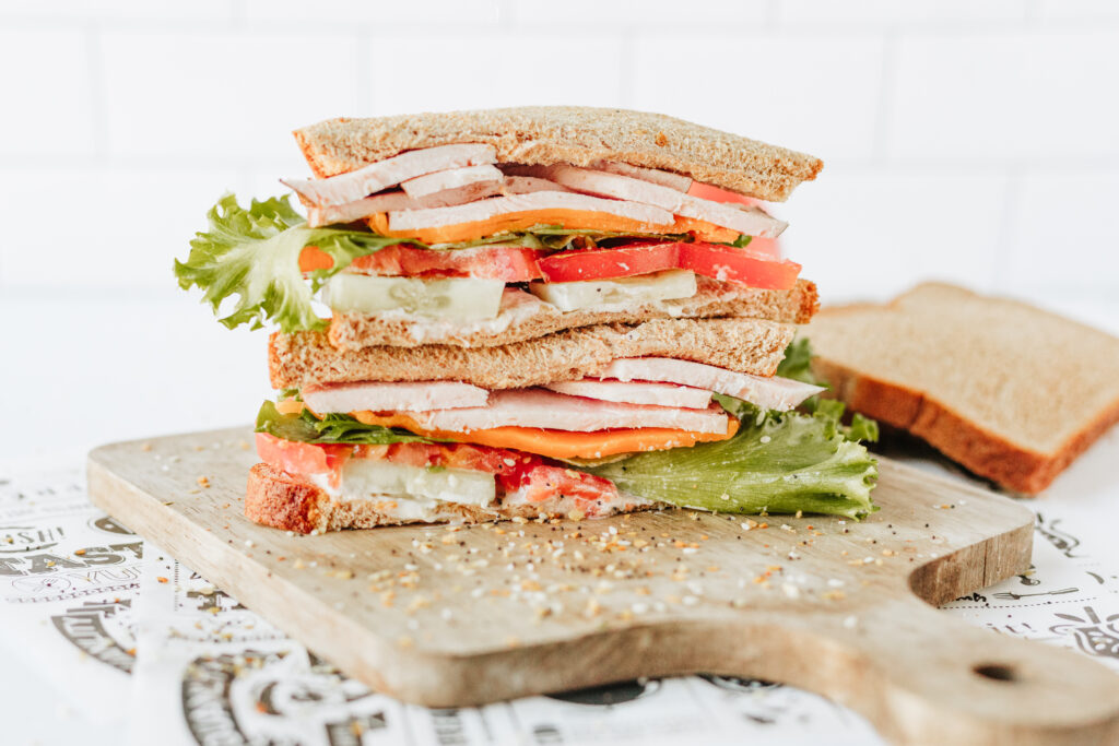 Customizable healthy sandwich showing layers of veggies, protein, cheese, and bread