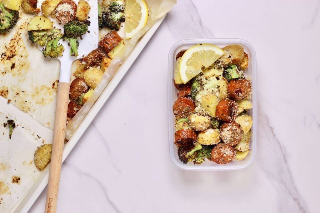 Sheet pan sausage and veggies in meal prep container and sheet pan on side