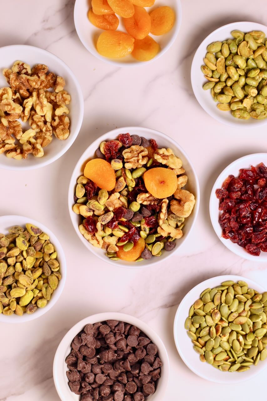 Homemade Trail Mix Recipe in white bowl with ingredients of your choice surrounding