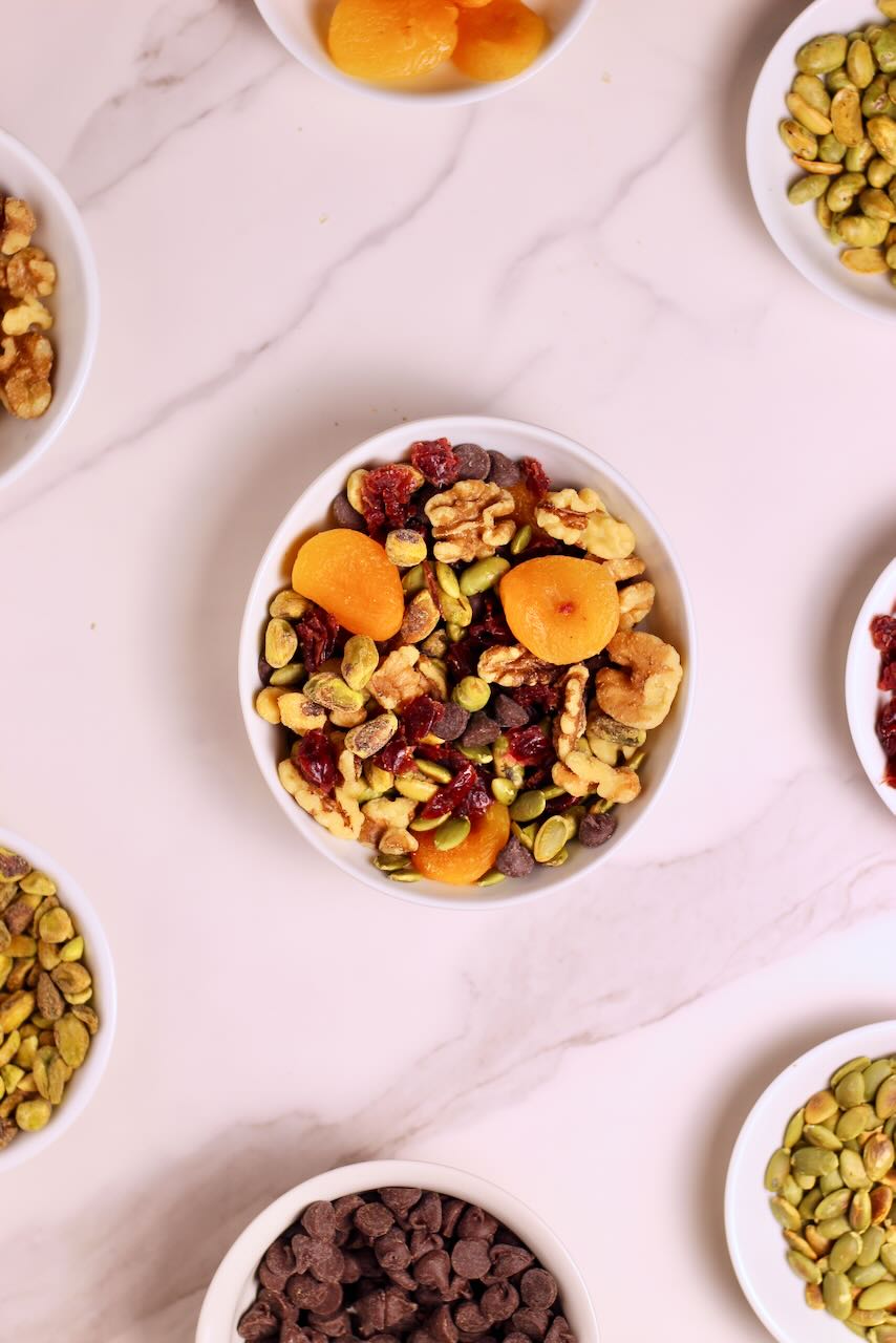 Homemade Trail Mix Recipe in white bowl with ingredients of your choice surrounding