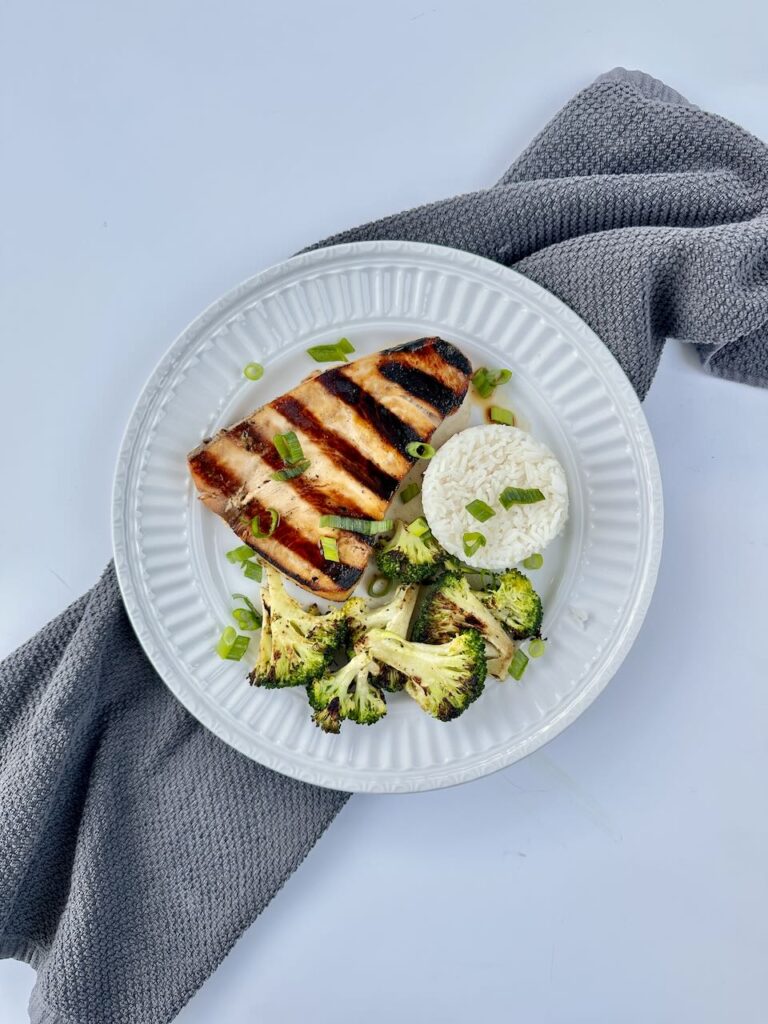 Swordfish on white plate with rice and broccoli