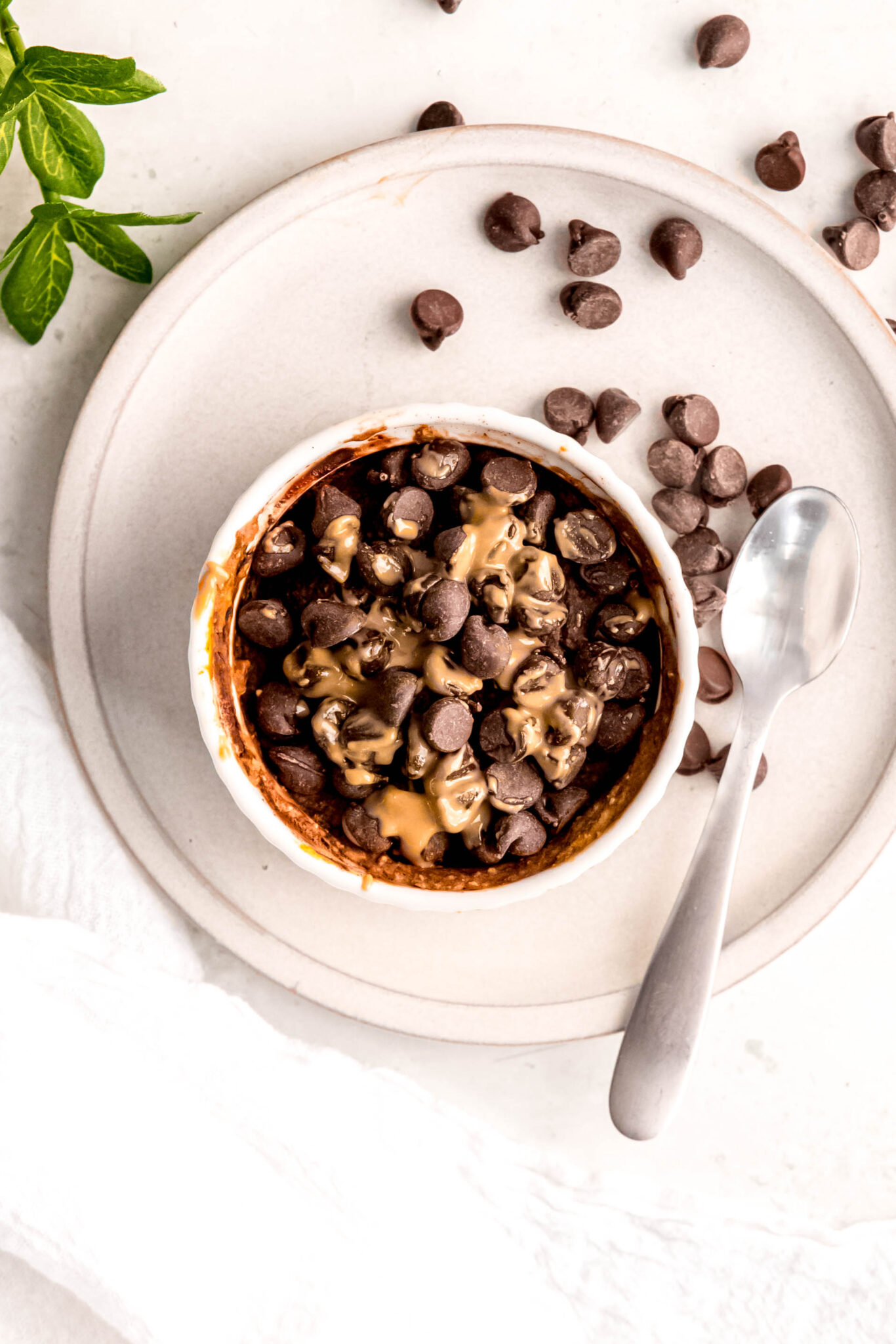 Chocolate baked oats in white ramekin and spoon on side