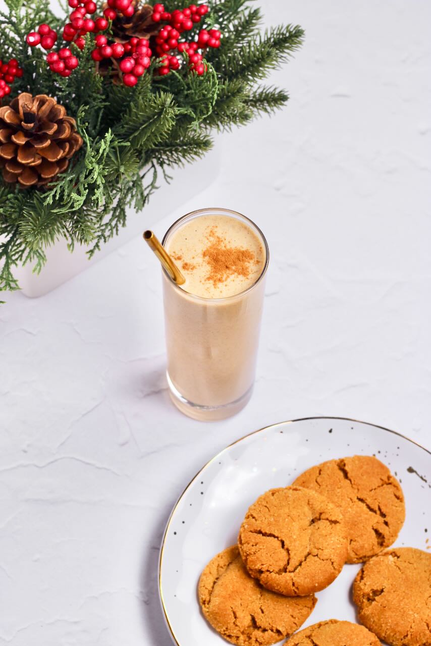 Gingerbread protein smoothie in glass with straw and cookies on plate