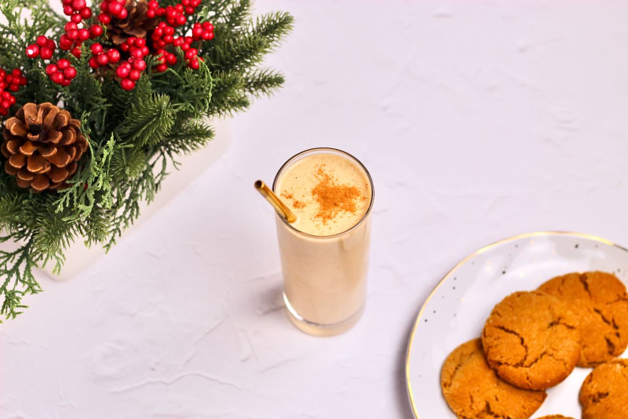 Gingerbread protein smoothie in glass with straw and cookies on the side