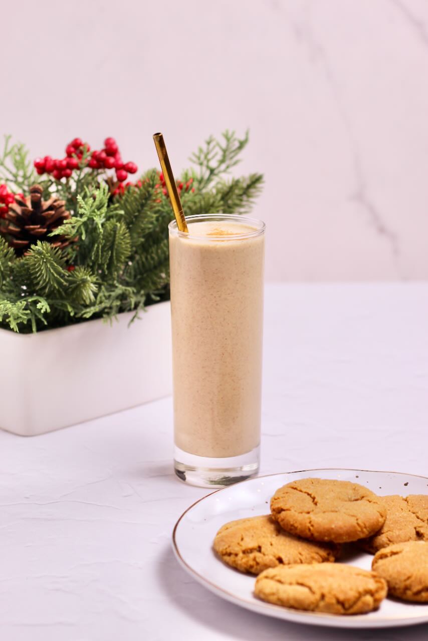Gingerbread protein smoothie in glass with straw and cookies on plate
