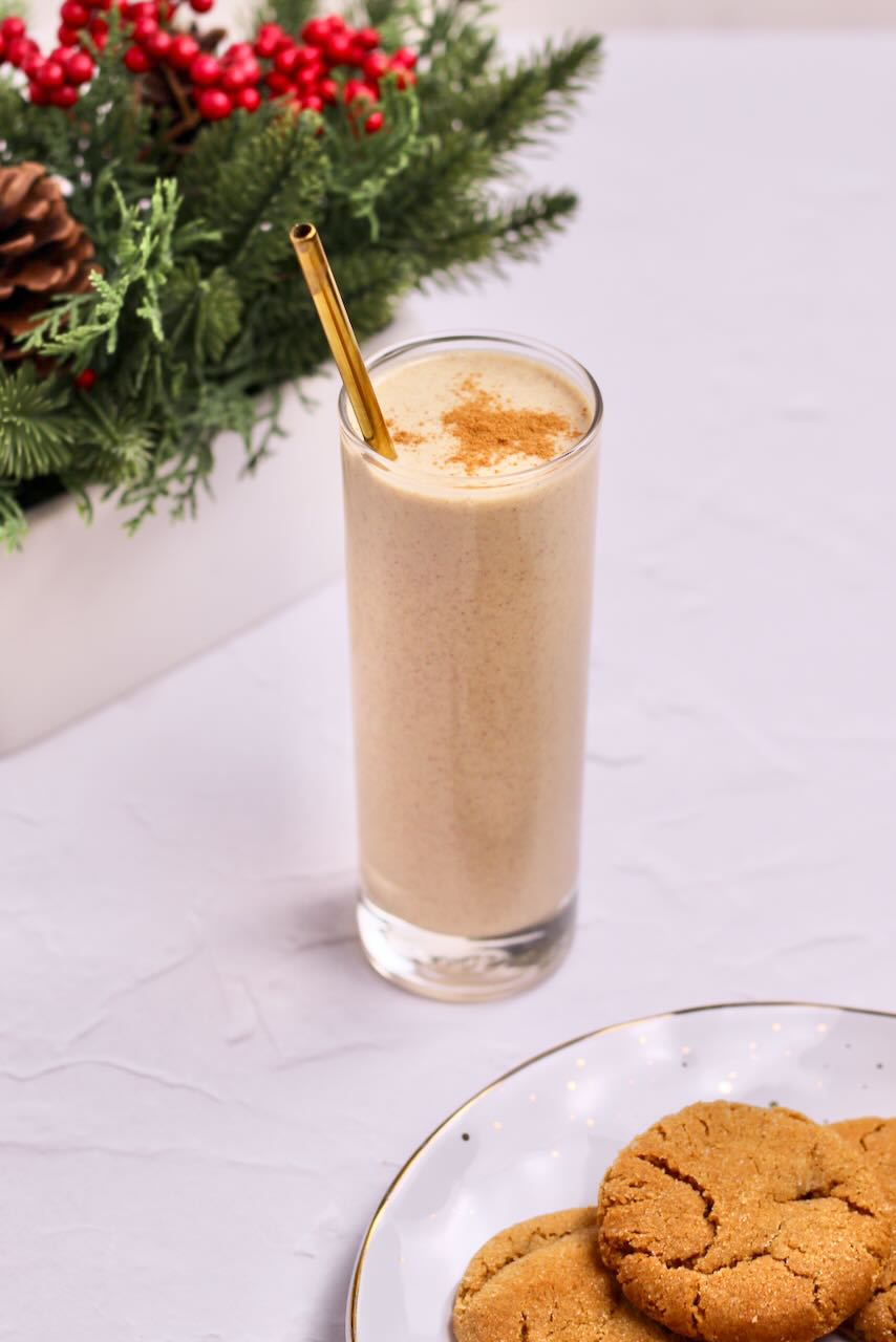 Gingerbread protein smoothie in glass with straw and cookies on plate