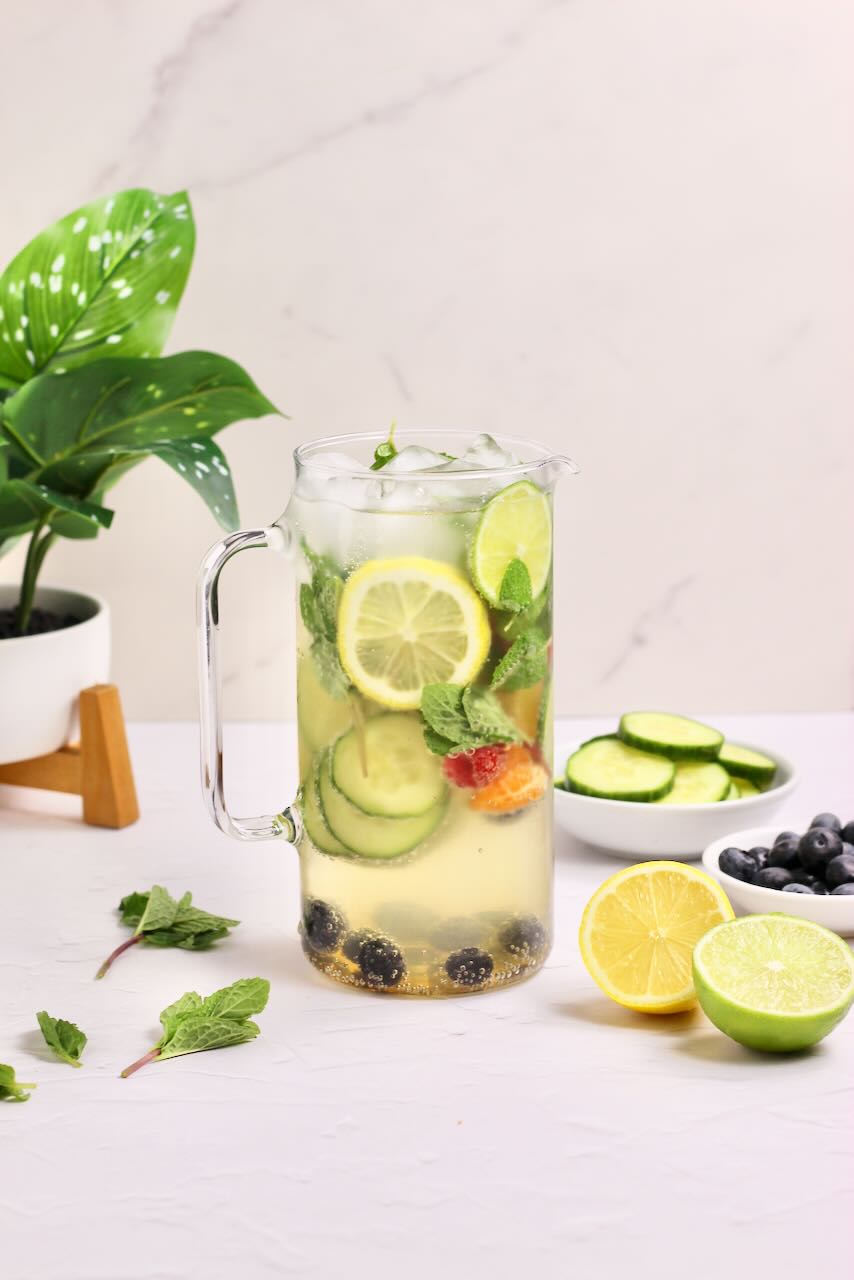 Infused water with lemons, limes, cucumbers, and blueberries in clear pitcher